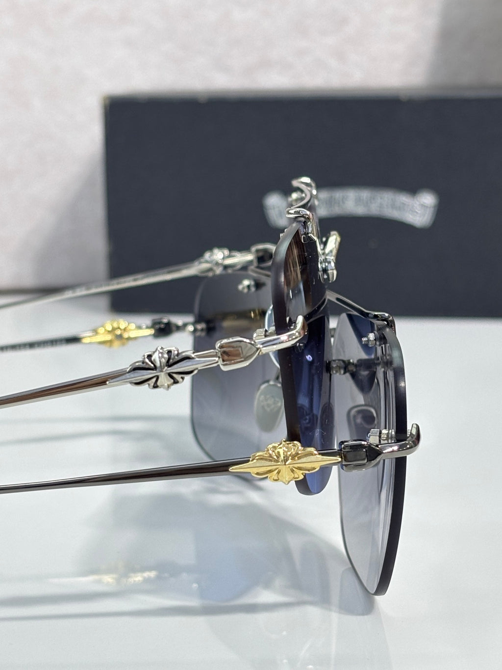 Chrome glasses close-up with blue lenses, ornate gold-tone temple details