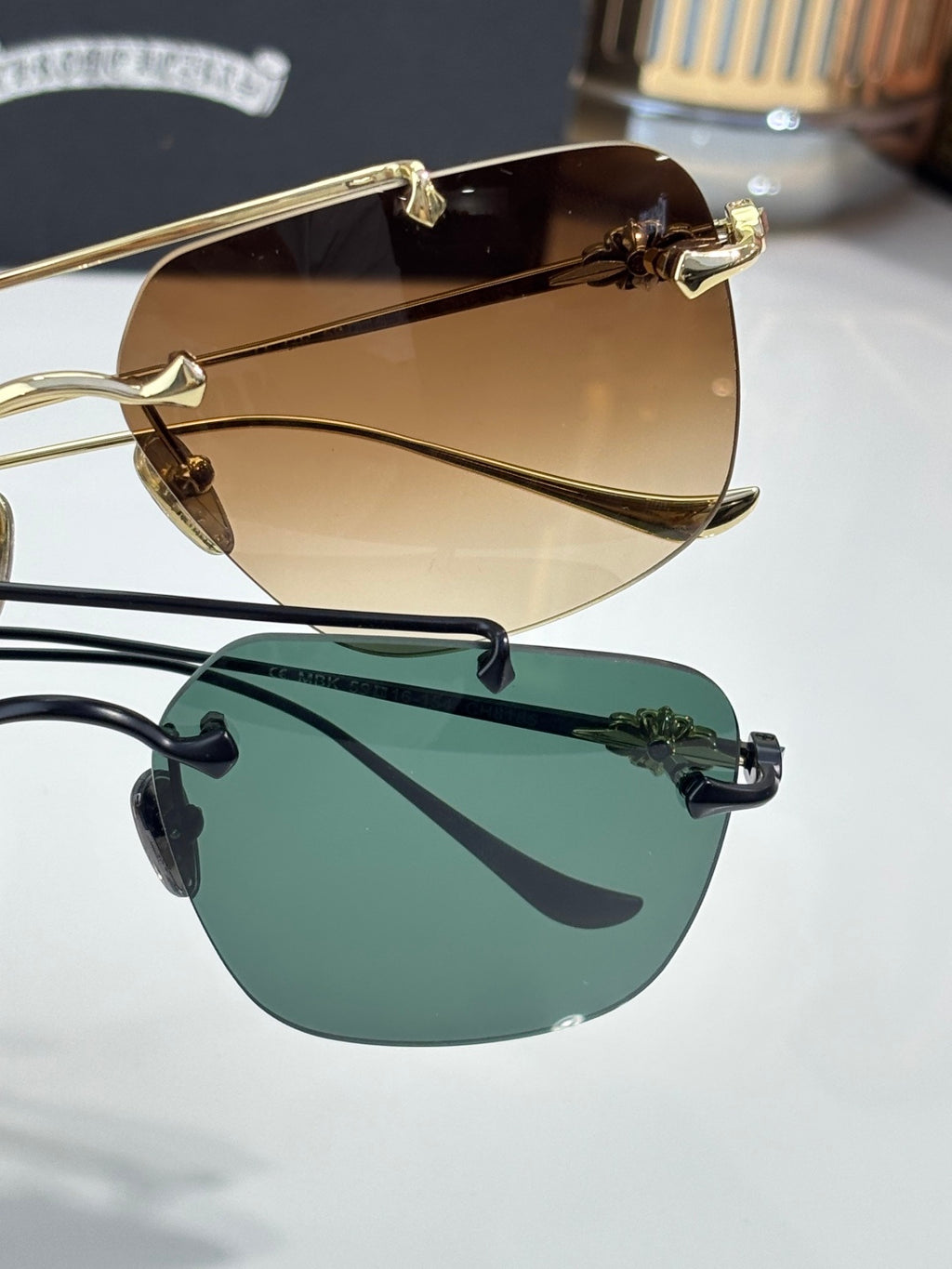 Chrome glasses set with brown and green tinted lenses, metal frames shown
