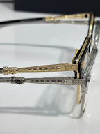 Close-up metal eyeglass hinge and gold-toned temple with engraved pattern