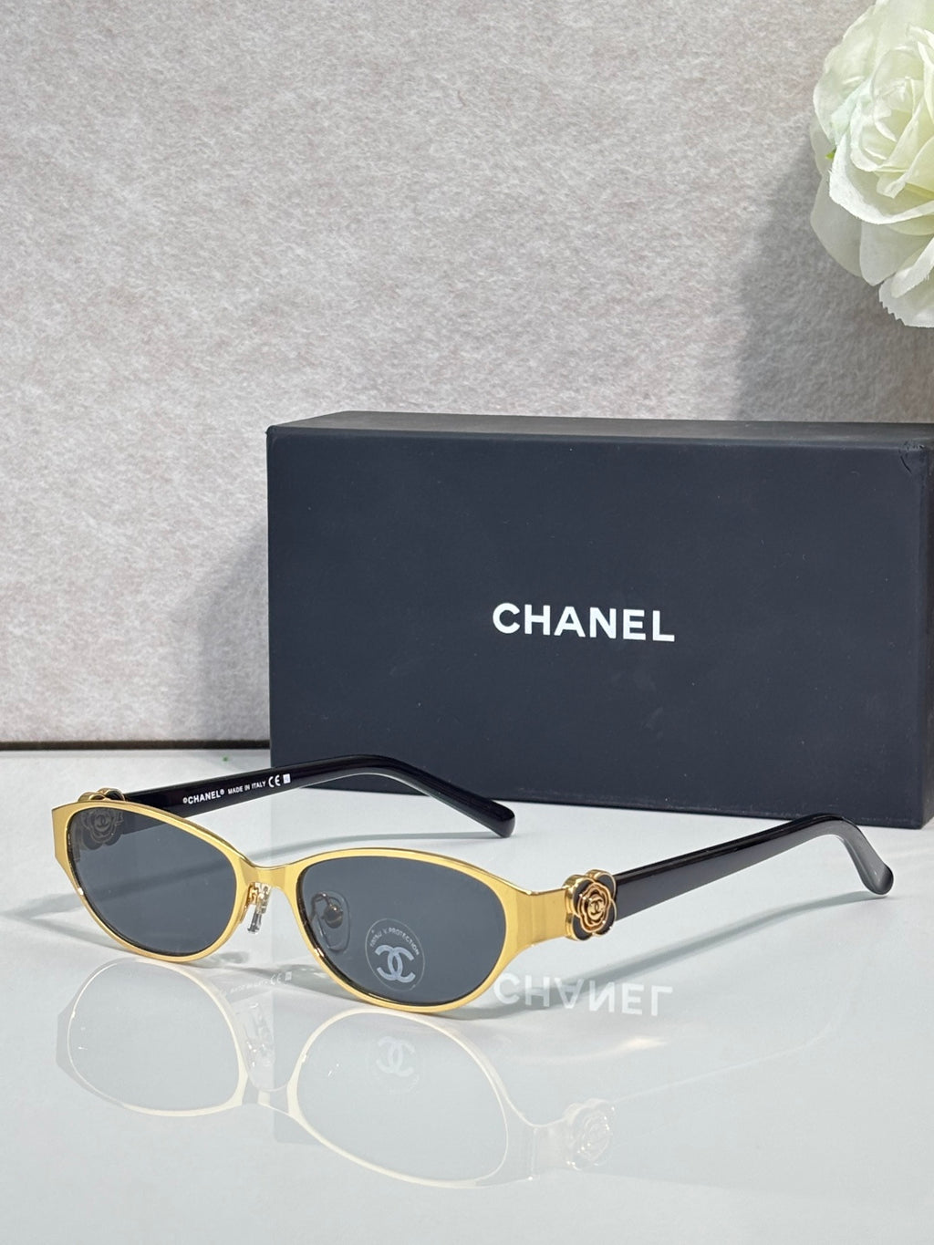 Oval sunglasses with gold frame, dark lenses, and ornate gold front detail