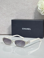 Oval sunglasses with white frame, light lenses, and silver flower hinge