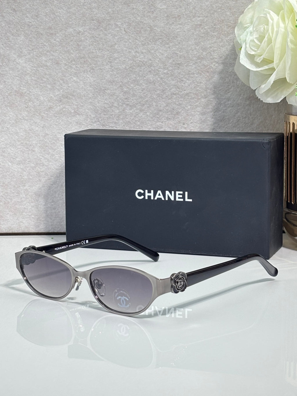 Oval sunglasses with silver frame, dark lenses, and black temple accents