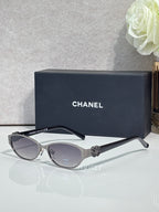 Oval sunglasses with silver frame, dark lenses, and black temple accents