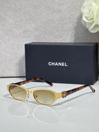 Oval sunglasses with tortoiseshell top, gold frame, and dark lenses