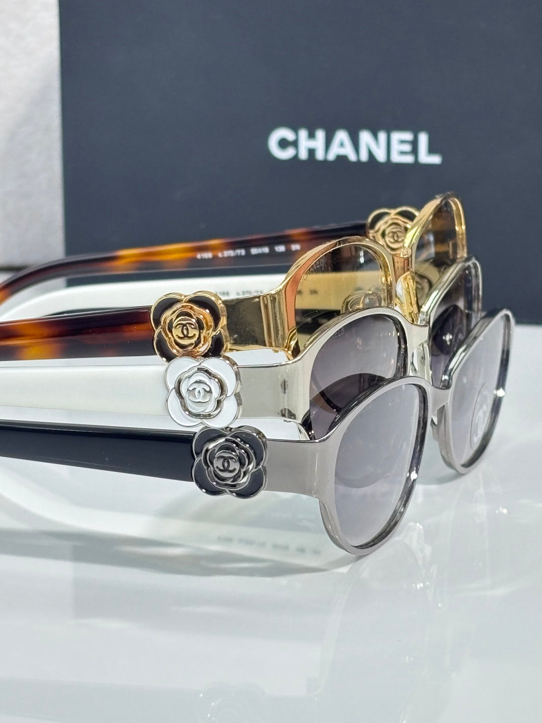 Close-up of oval sunglasses with gold and clear frames and floral hardware