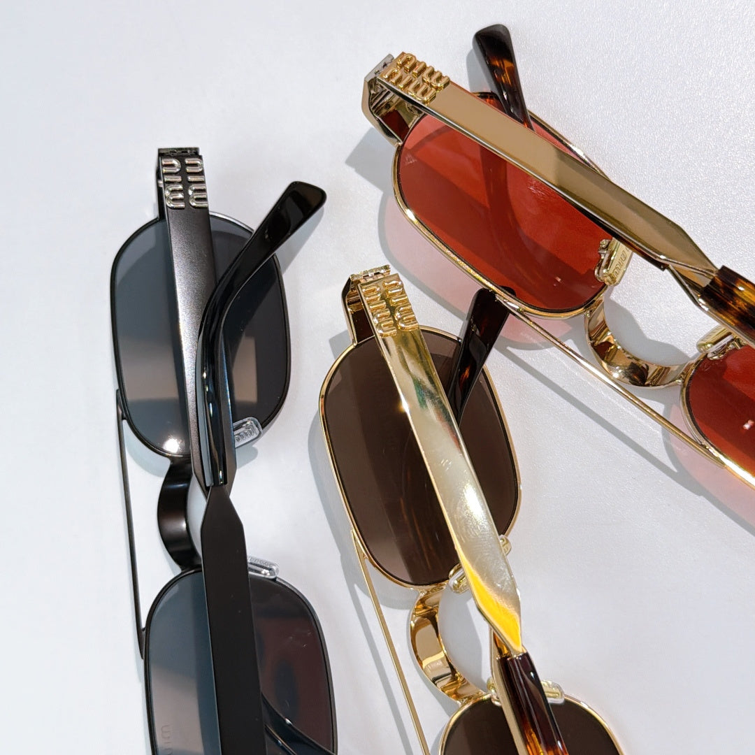 Gold sunglasses with red tinted lenses and engraved temple details, close-up