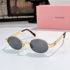 MiuMiu round sunglasses with gold frames, dark blue lenses, and tortoiseshell temple tips