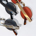 MiuMiu round sunglasses close-up with black and gold frames and dark lenses