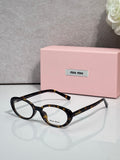 MiuMiu eyeglasses, dark tortoiseshell round frames with transparent lenses.