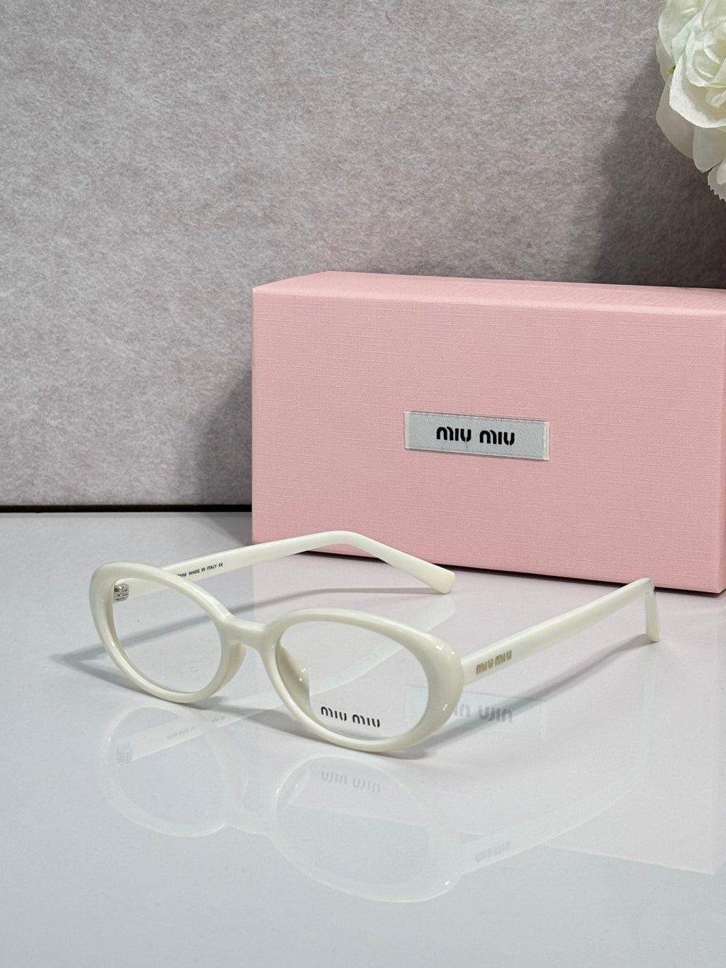 Eyeglasses with cream white round frames and clear lenses, branding on temple.