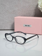 Eyeglasses with dark round frames and clear lenses, curved top temple.