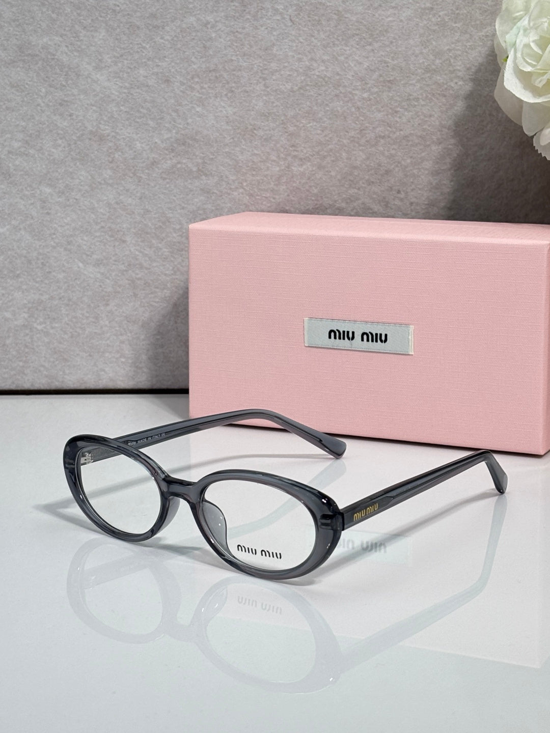 Eyeglasses with dark round frames and clear lenses, curved top temple.