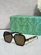 Gucci sunglasses with black frame, tinted lenses, and gold horsebit detail