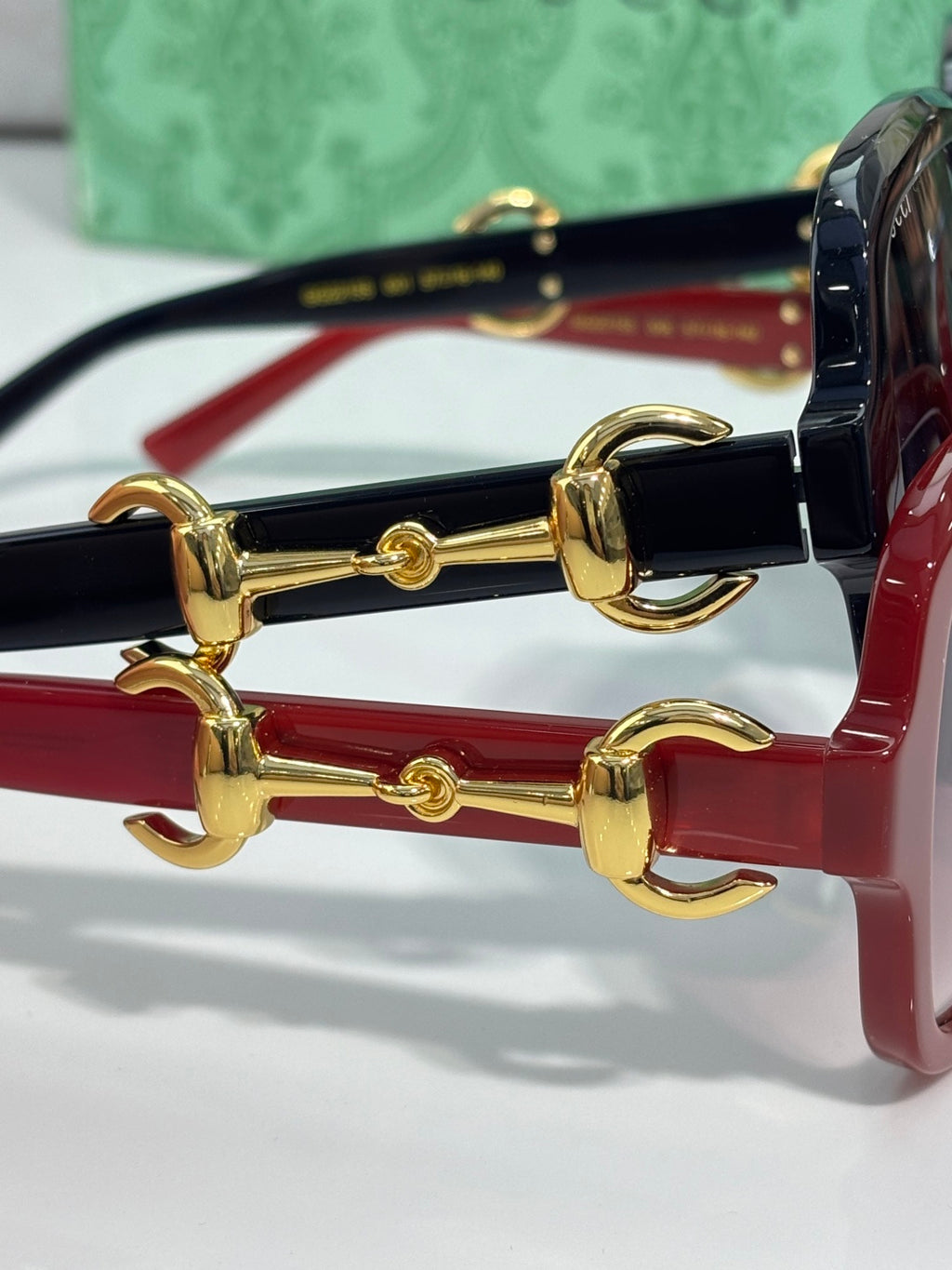 Gucci sunglasses close-up: gold horsebit hardware on red and black frames