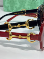 Gucci sunglasses close-up: gold horsebit hardware on red and black frames
