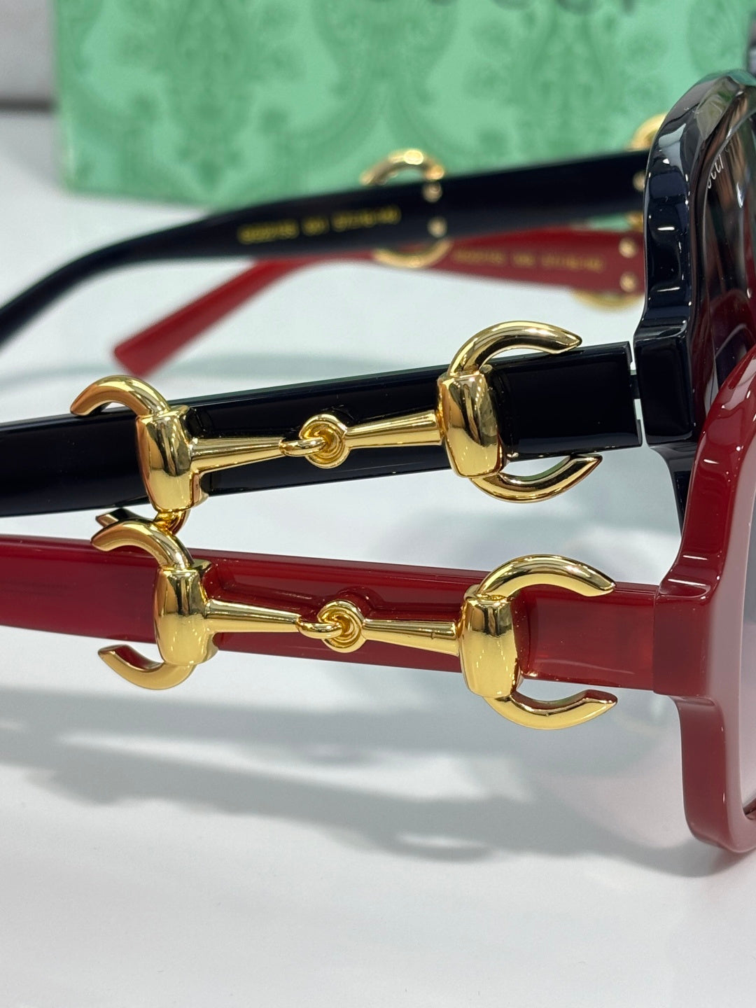 Gucci sunglasses close-up: gold horsebit hardware on red and black frames