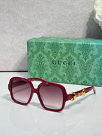 Gucci sunglasses with red frame, tinted lenses, and gold horsebit detail