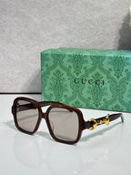 Gucci sunglasses with dark brown frame, tinted lenses, and gold horsebit detail