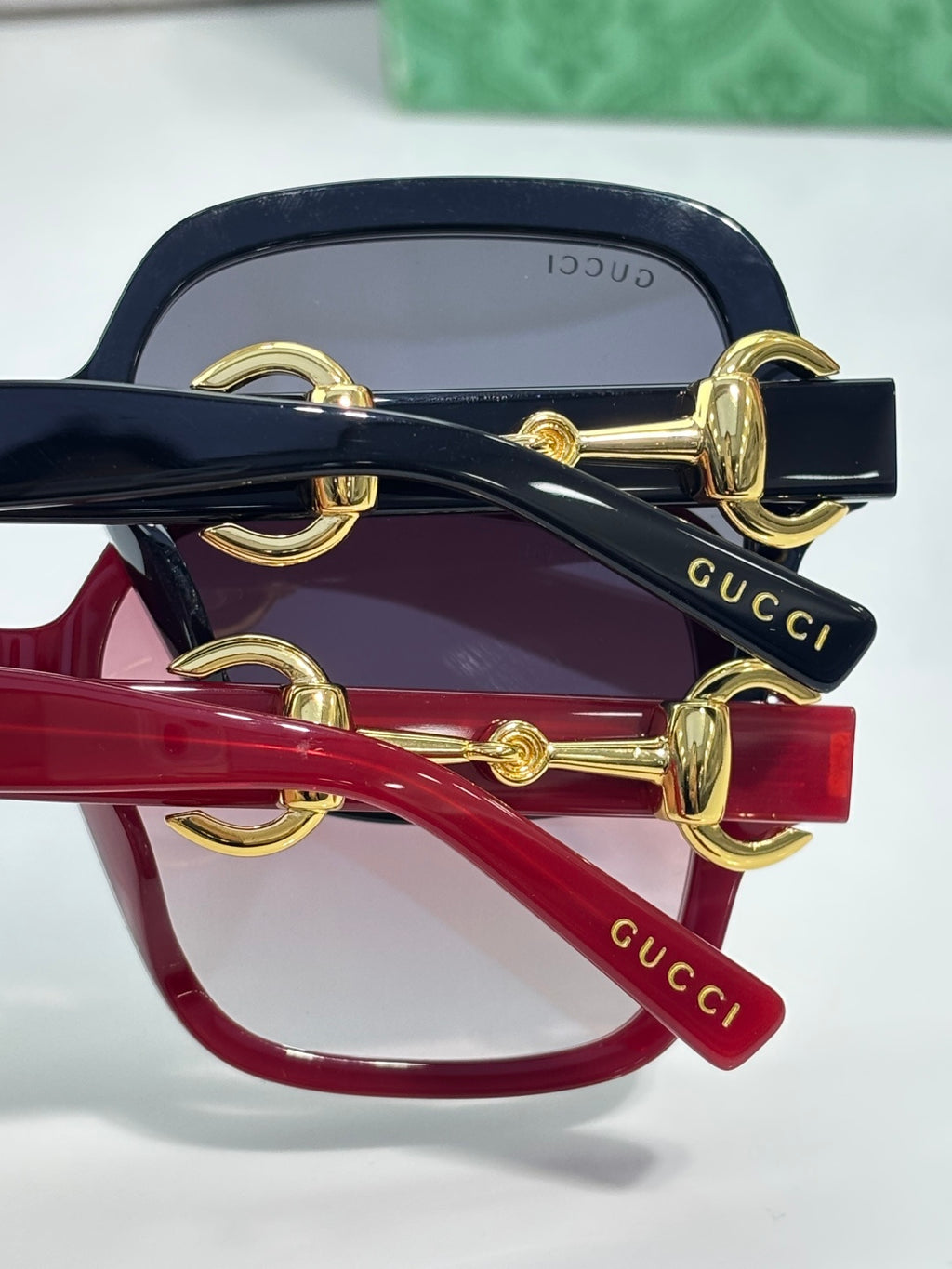 Gucci sunglasses close-up of gold hinge hardware on navy and red frames