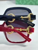 Gucci sunglasses close-up of gold hinge hardware on navy and red frames