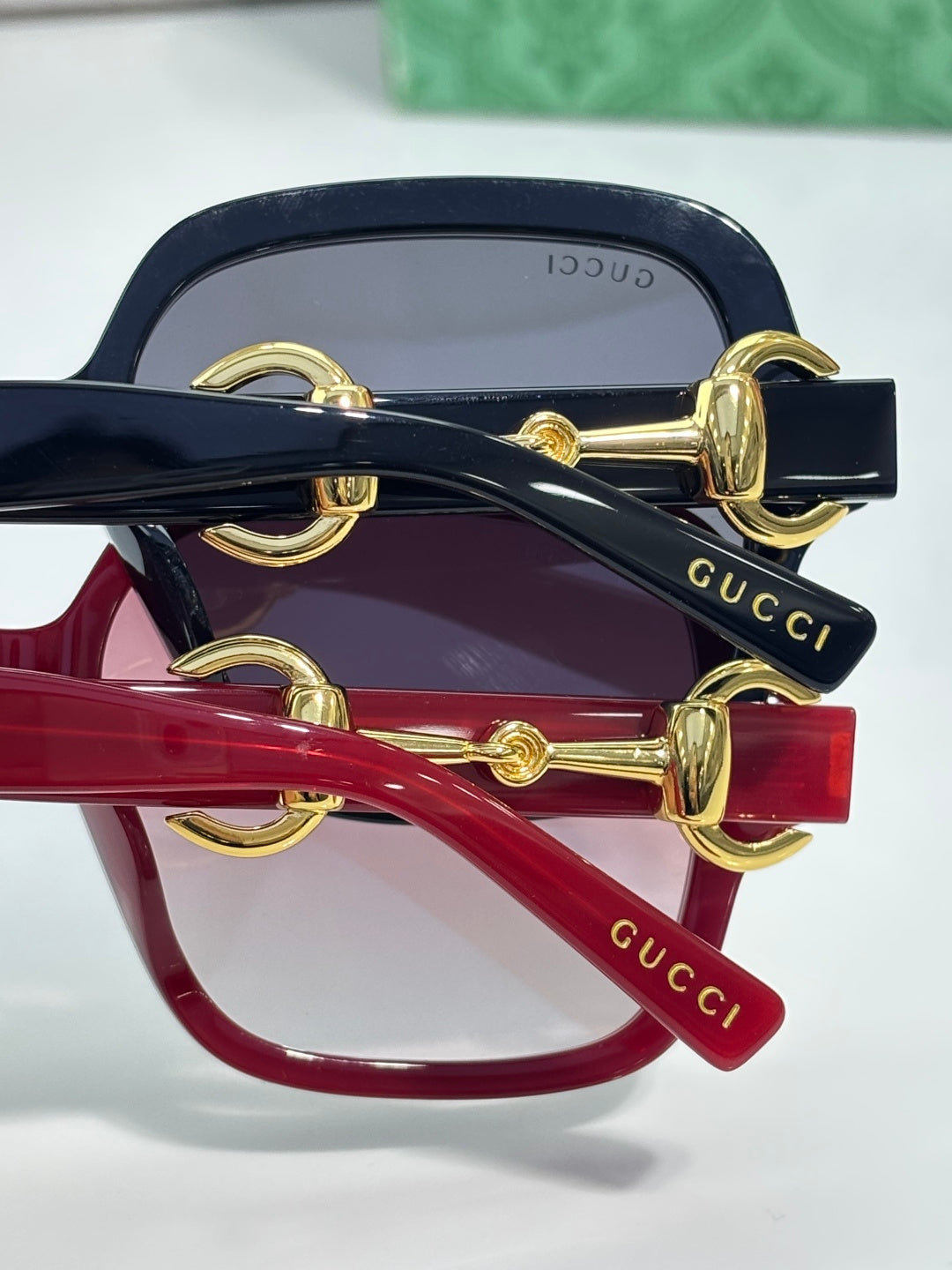 Gucci sunglasses close-up of gold hinge hardware on navy and red frames