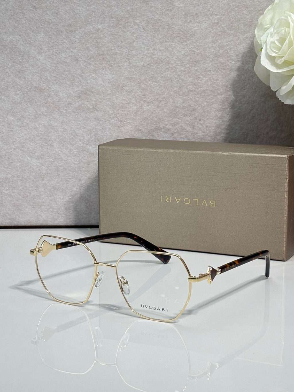 Gold metal round eyeglasses with clear lenses and dark tortoise temple tips, logo.