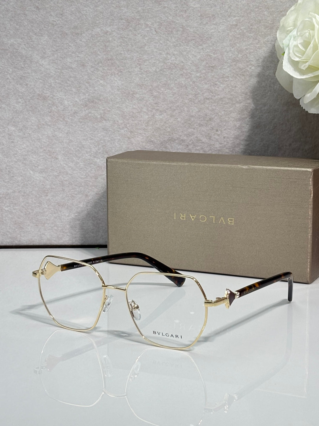 Gold metal round eyeglasses with clear lenses and dark tortoise temple tips, logo.