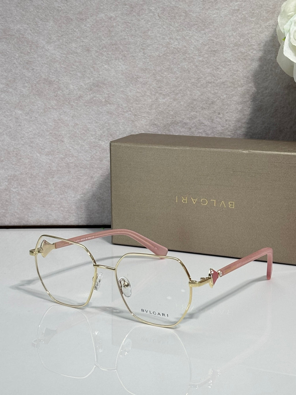 Gold metal round eyeglasses with clear lenses and pink-tinted temple accents, logo.