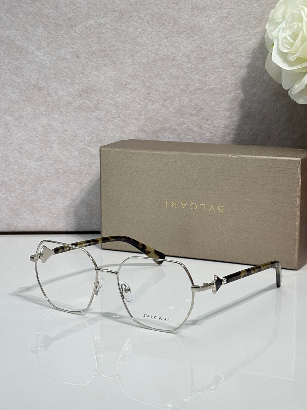 Gold metal round eyeglasses with clear lenses and dark tortoise accents, logo on lens.