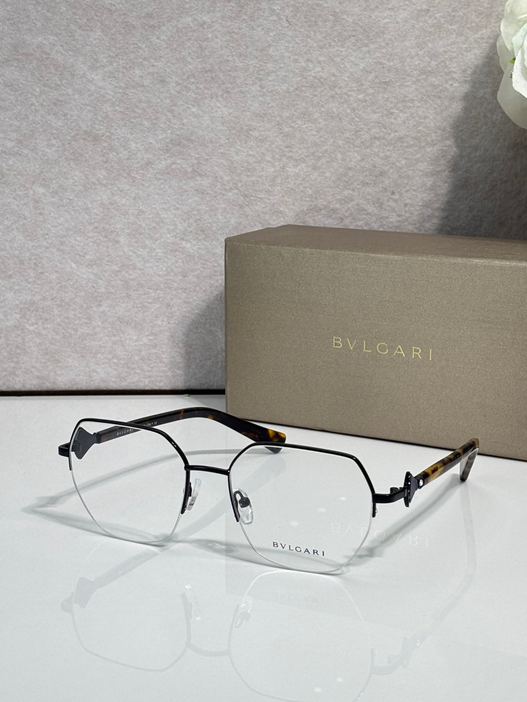 Eyeglasses with clear lenses and black metal frame, tortoiseshell top detail on bridge.
