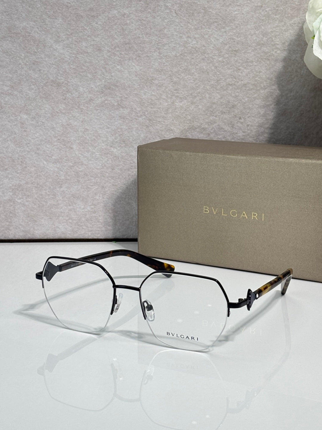 Eyeglasses with clear lenses and black metal frame, tortoiseshell top detail on bridge.
