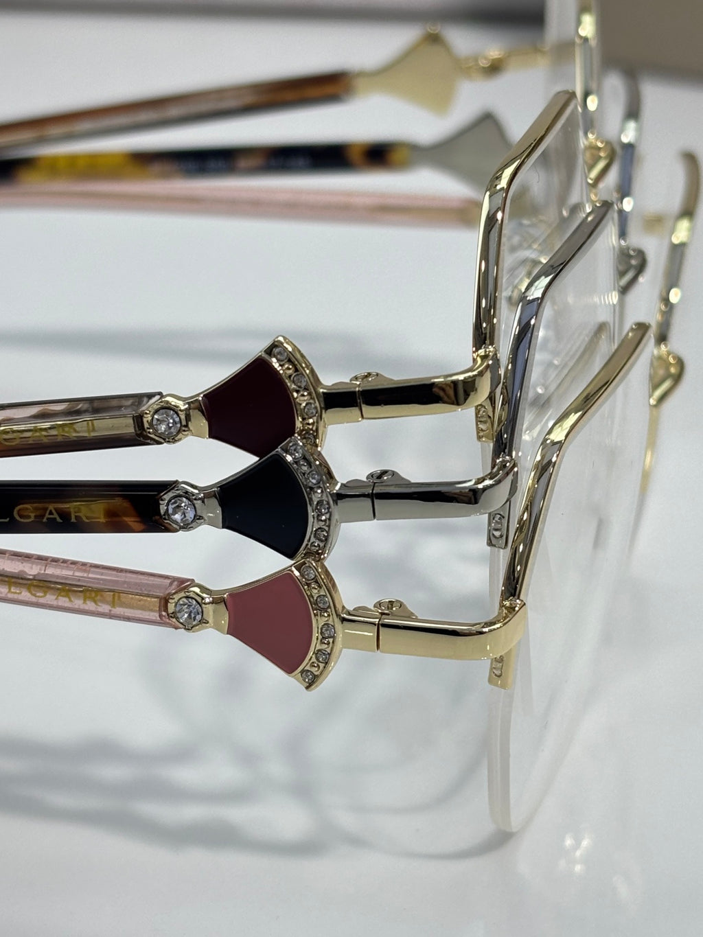 Eyeglasses close-up: decorative rhinestone hinge with colored temple accents, gold-tone.