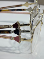 Eyeglasses close-up: decorative rhinestone hinge with colored temple accents, gold-tone.