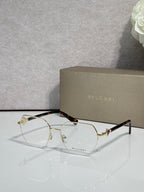 Eyeglasses with clear lenses and gold-tone metal frame, tortoiseshell temples.