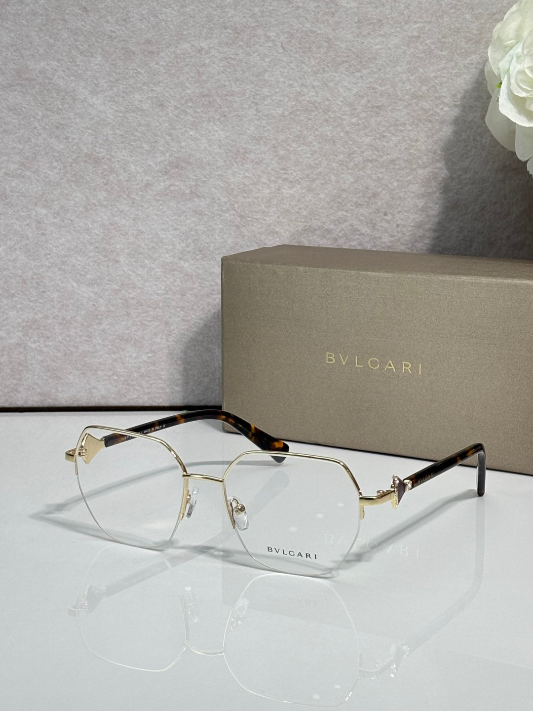 Eyeglasses with clear lenses and gold-tone metal frame, tortoiseshell temples.