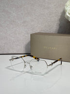 Eyeglasses with clear lenses and gold-tone metal frame, tortoiseshell top bar.