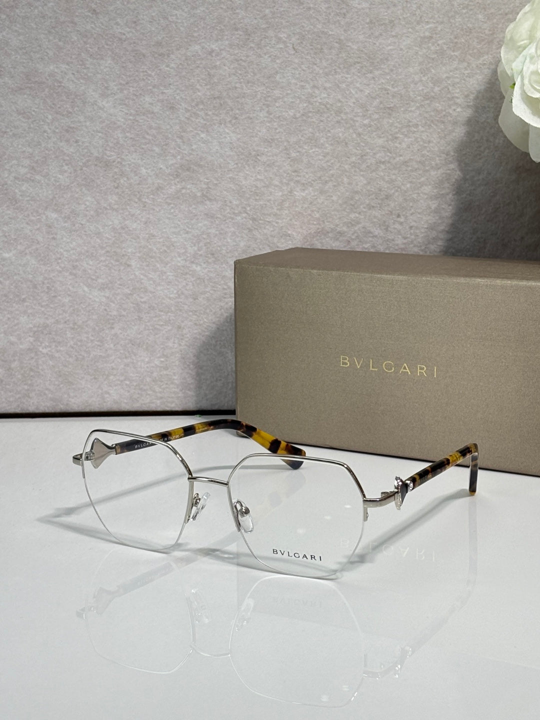Eyeglasses with clear lenses and gold-tone metal frame, tortoiseshell top bar.