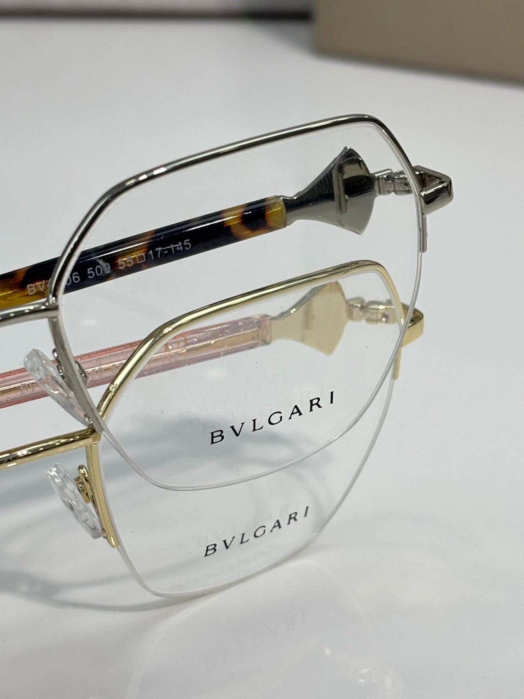 Eyeglasses close-up: tortoiseshell temple with pink accent, gold-tone metal frame.