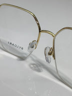 Eyeglasses close-up: gold-tone frame with engraved temple, clear lenses and bridge.