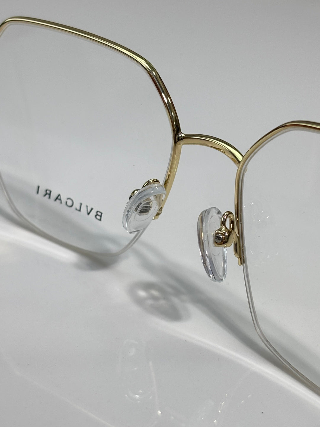 Eyeglasses close-up: gold-tone frame with engraved temple, clear lenses and bridge.