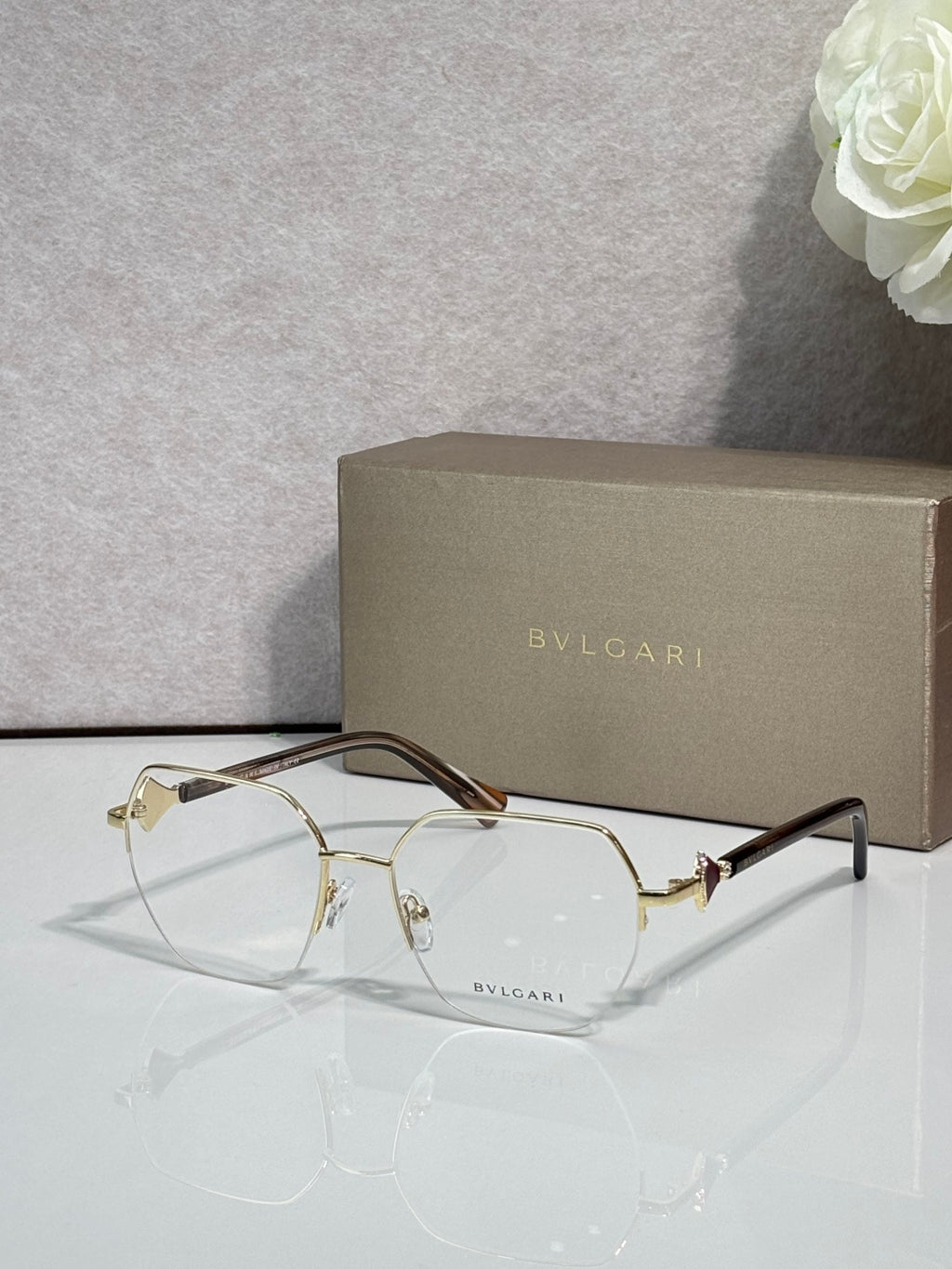 Eyeglasses with clear lenses and gold-tone metal frame, dark brown temple accents.