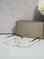 Eyeglasses with clear lenses and gold-tone metal frame, dark brown temple accents.