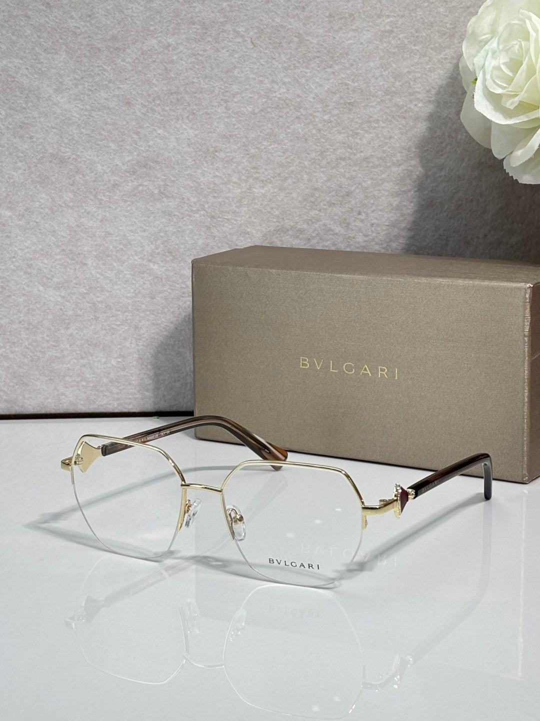 Eyeglasses with clear lenses and gold-tone metal frame, dark brown temple accents.
