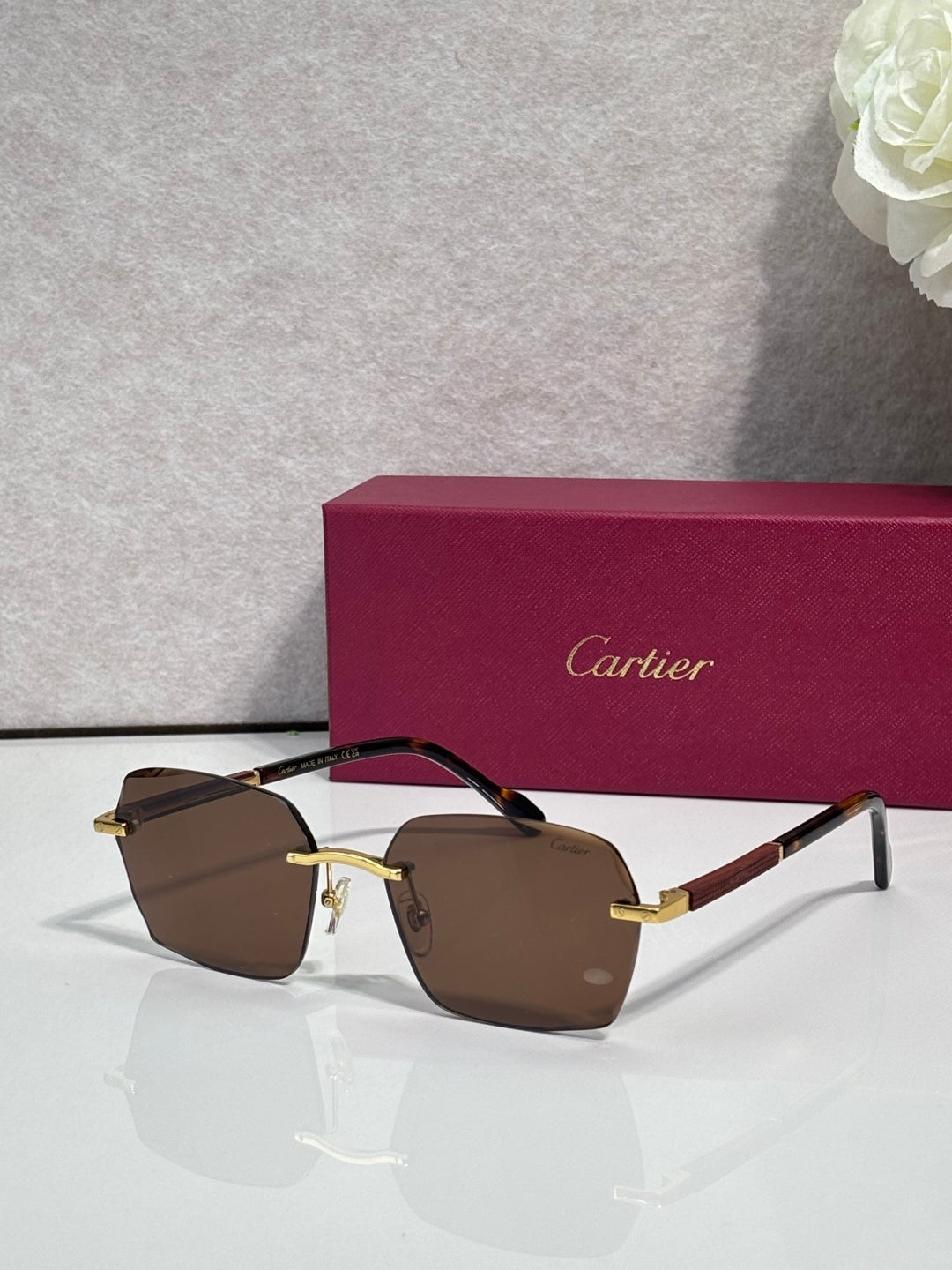 Cartier sunglasses with brown-tinted lenses, dark frame, and gold metal accents.