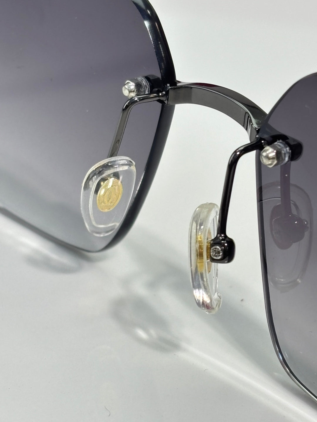 Cartier sunglasses close-up: black frame with round gold emblem on the temple.