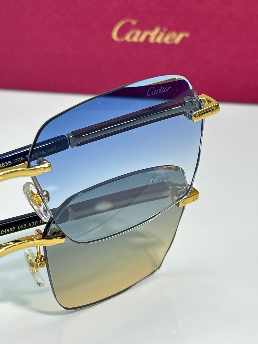 Cartier sunglasses close-up: gold hinge on blue gradient lenses with dark frame.