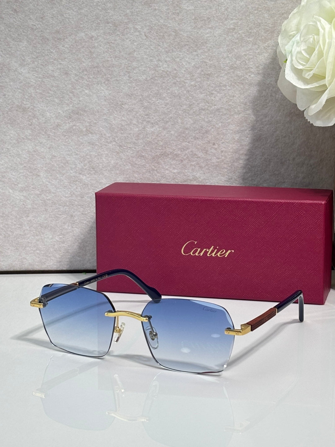 Cartier sunglasses with light blue lenses, black frame, and gold metal accents.