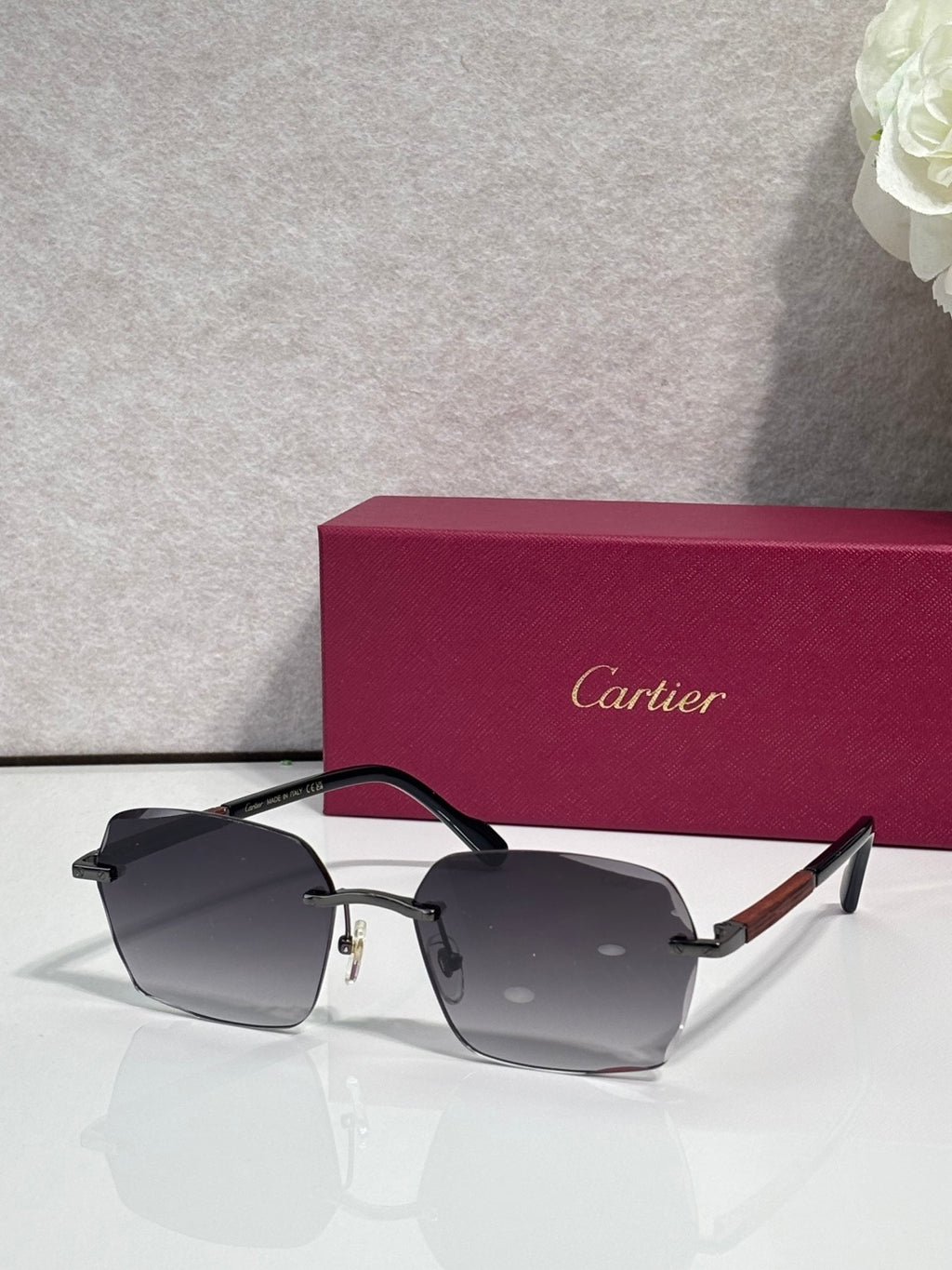 Cartier sunglasses with dark grey lenses, black frame, and gold metal accents.