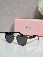 Black cat-eye style glasses with dark gradient lenses and gold-tone hardware