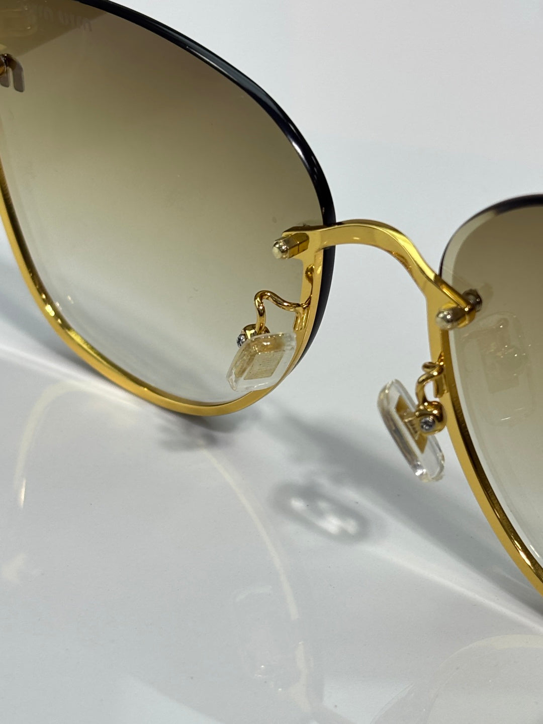 Gold-tone round glasses hinge and temple detail with translucent frame sections
